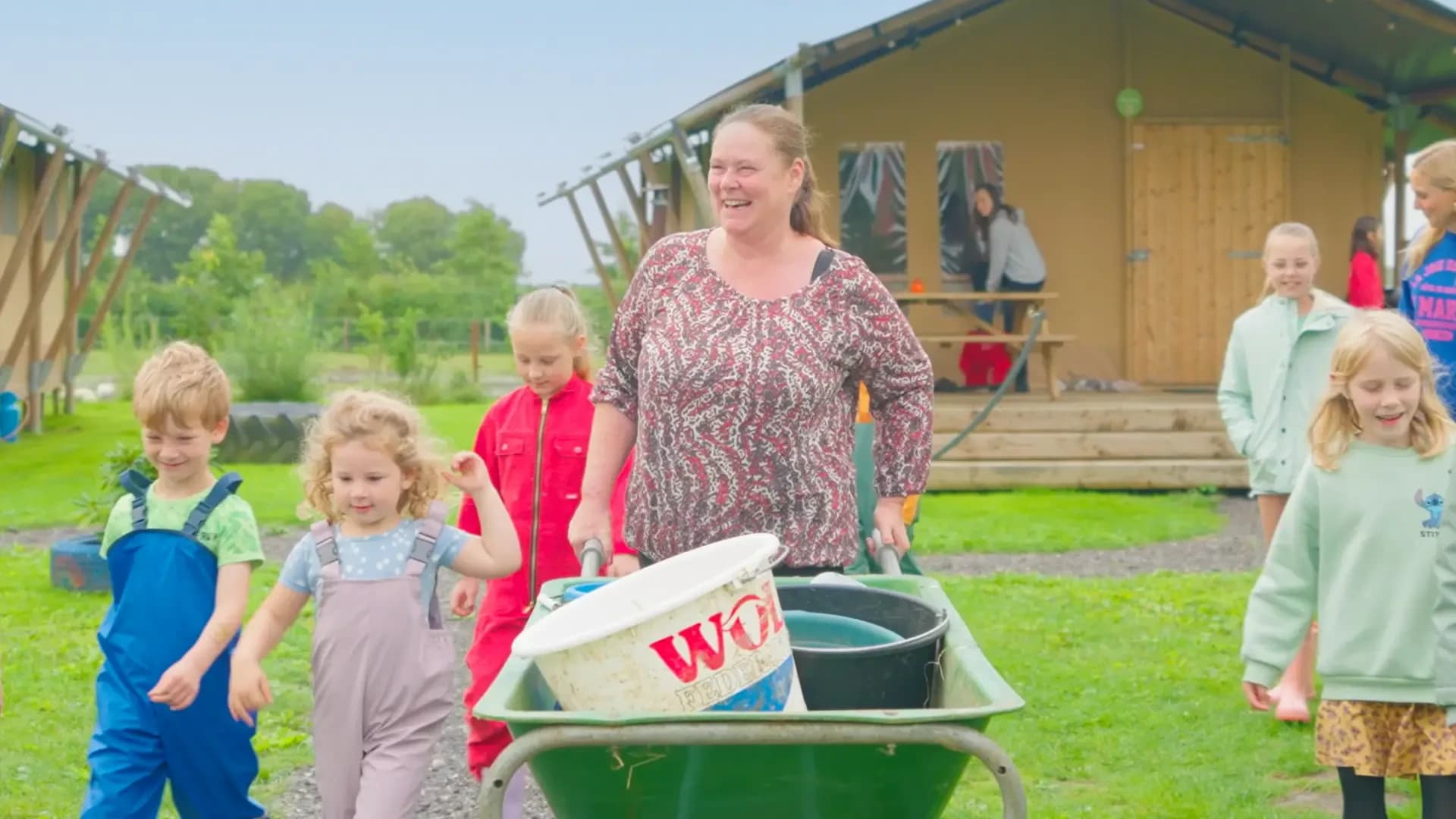 FarmCamps De Bonte Fries Friesland boerin vrolijk kinderen lopen kruiwagen tent lodge