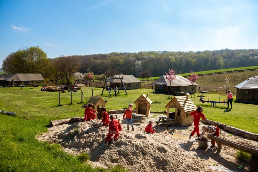 kinderen spelen in de zandbak bij safaritenten