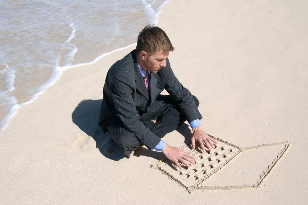 zakenman-met-notebook-in-het-zand