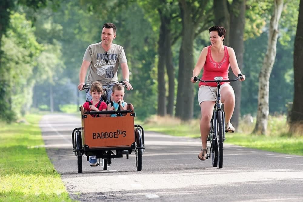 Gezin fietst langs het Pieterpad met kinderen in een groene omgeving