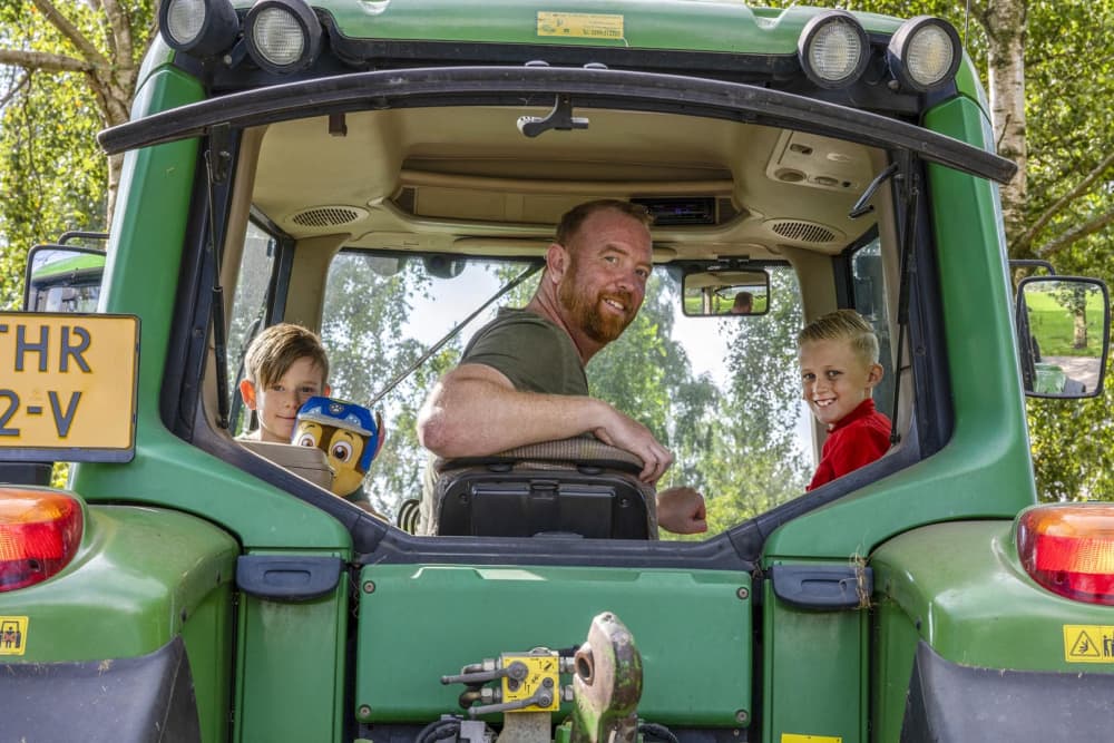 boer in de traktor met 2 kinderen