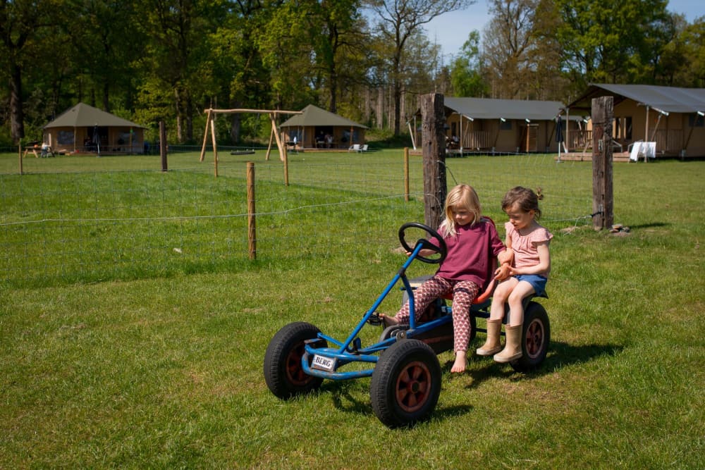 Child happily riding a pedal go-kart during a weekend getaway on the farm