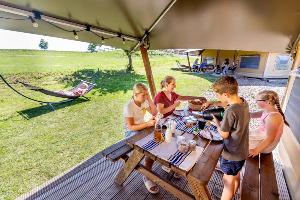 Gezin voor luxe tent op een mini camping van FarmCamps, omringd door natuur