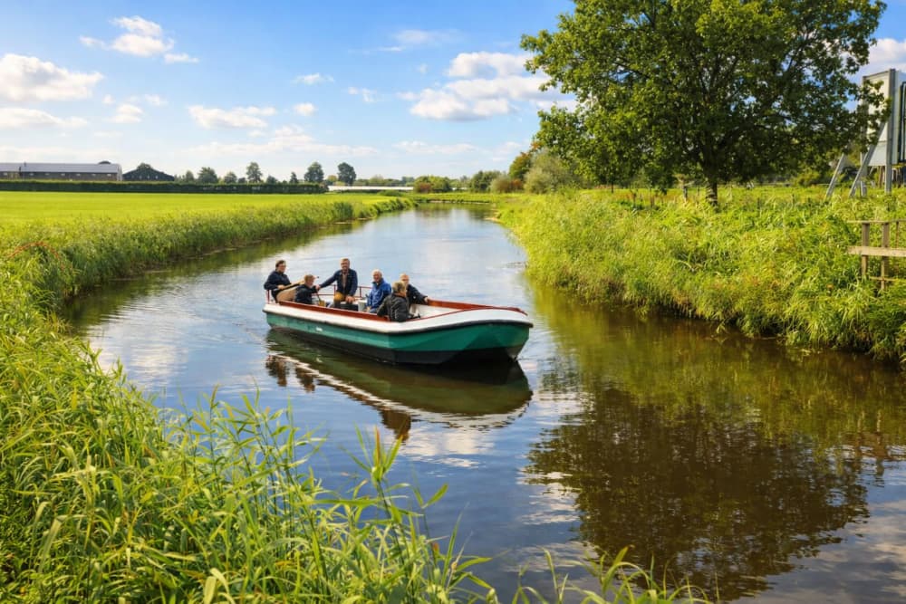 Mensen varen met een boot door de grachten in de natuur bij Giethoorn