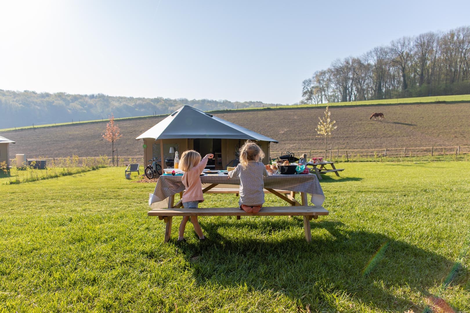 FarmCamps_De_Verloren_Kost_Zuid-Limburg_paasontbijt_kinderen_voor_de_tent_meisje_wijst_naar_paard_in_de_wei