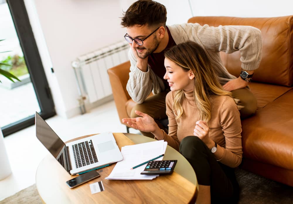 two people looking at a computer while sitting on a couch 