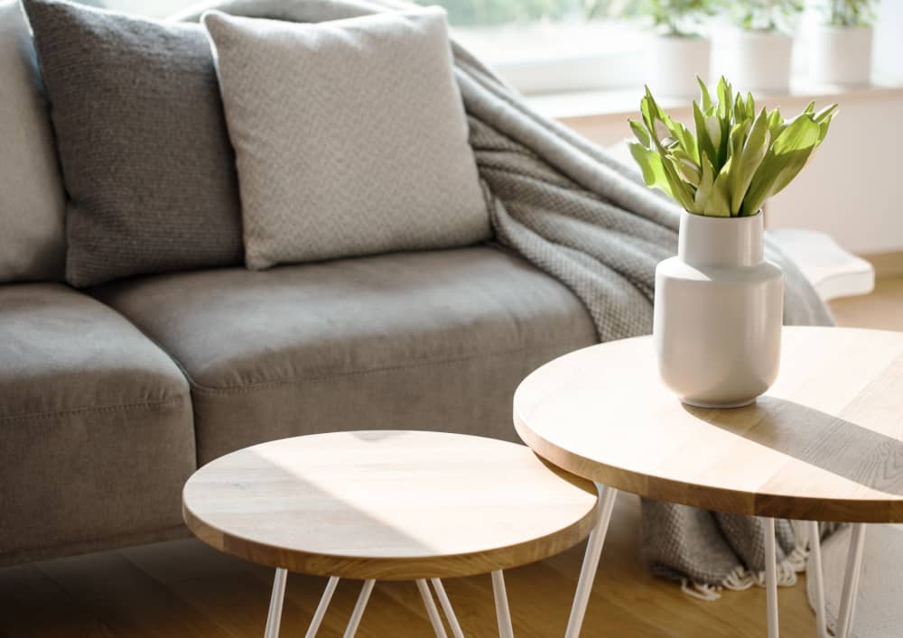 grey couch in an apartment and a side table in front of it with flowers 