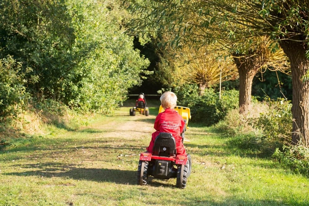 Een jongetje rijdt op de tractor tijdens de meivakantie bij FarmCamps