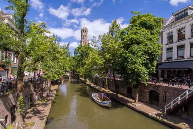 Canal flowing through Utrecht with trees on the side of the road